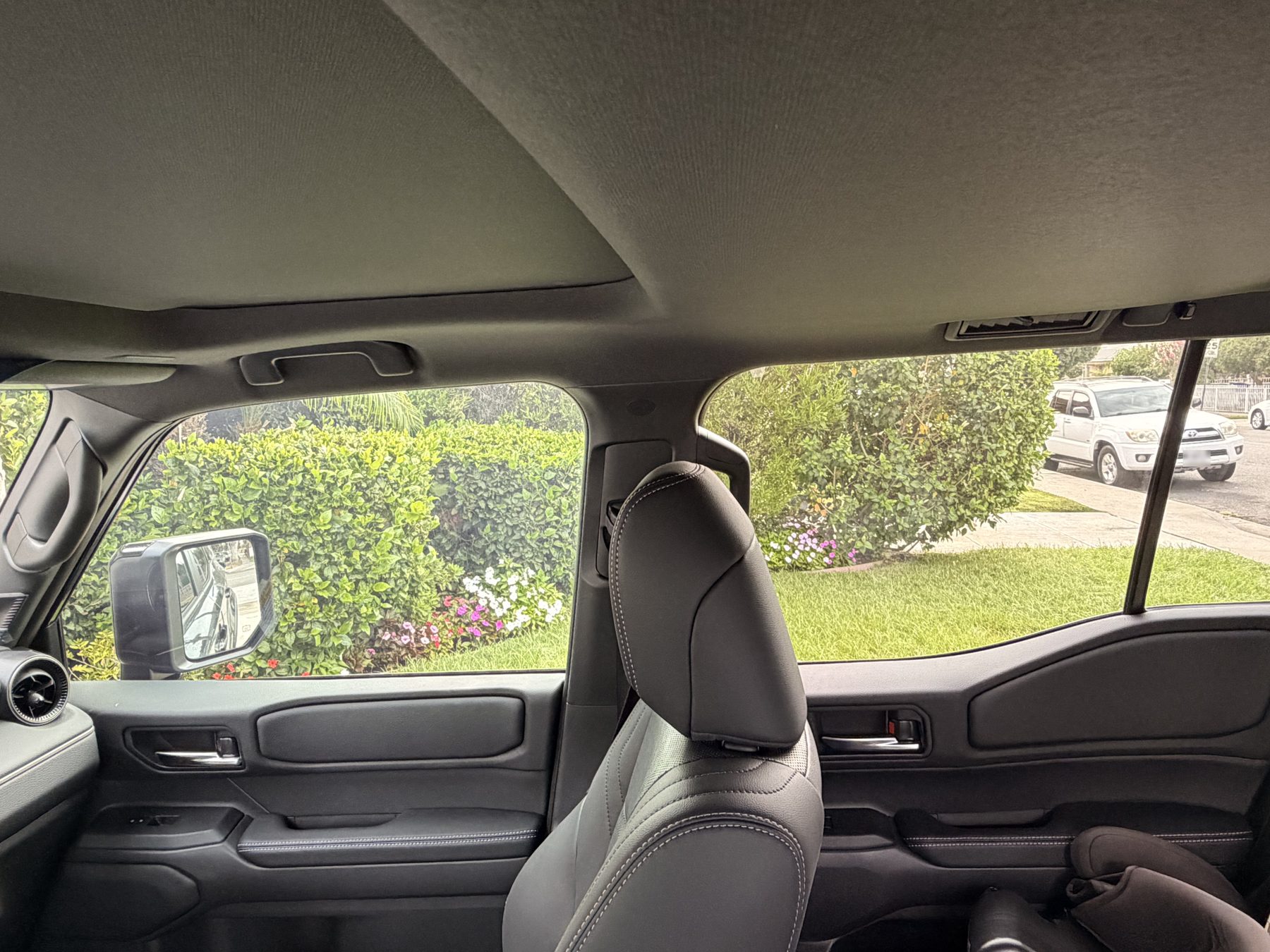 View from inside the same SUV before tinting, with bright washed-out daylight pouring straight through the clear side windows